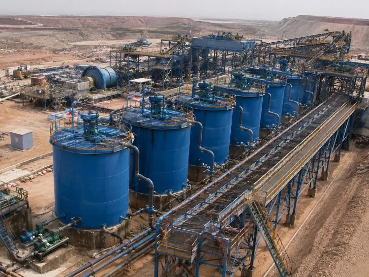Elevated view of multiple blue leaching tanks connected by walkways and piping
